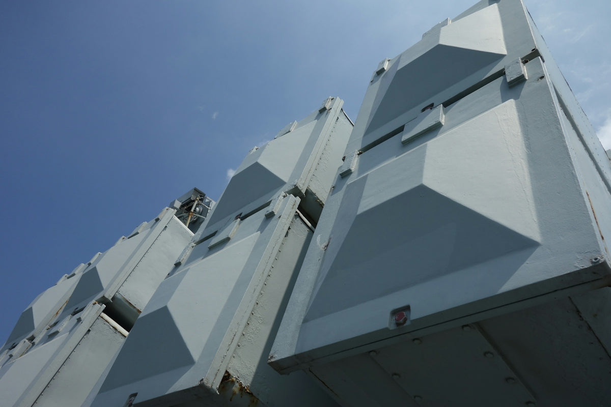 Large grey industrial structures against a clear blue sky